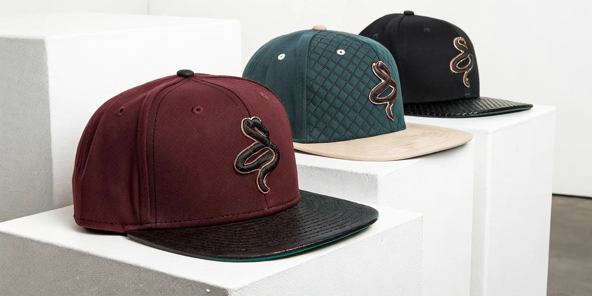 Beisbol Diamond Backs 31 hats in burgundy, green, and black with the snake logo.