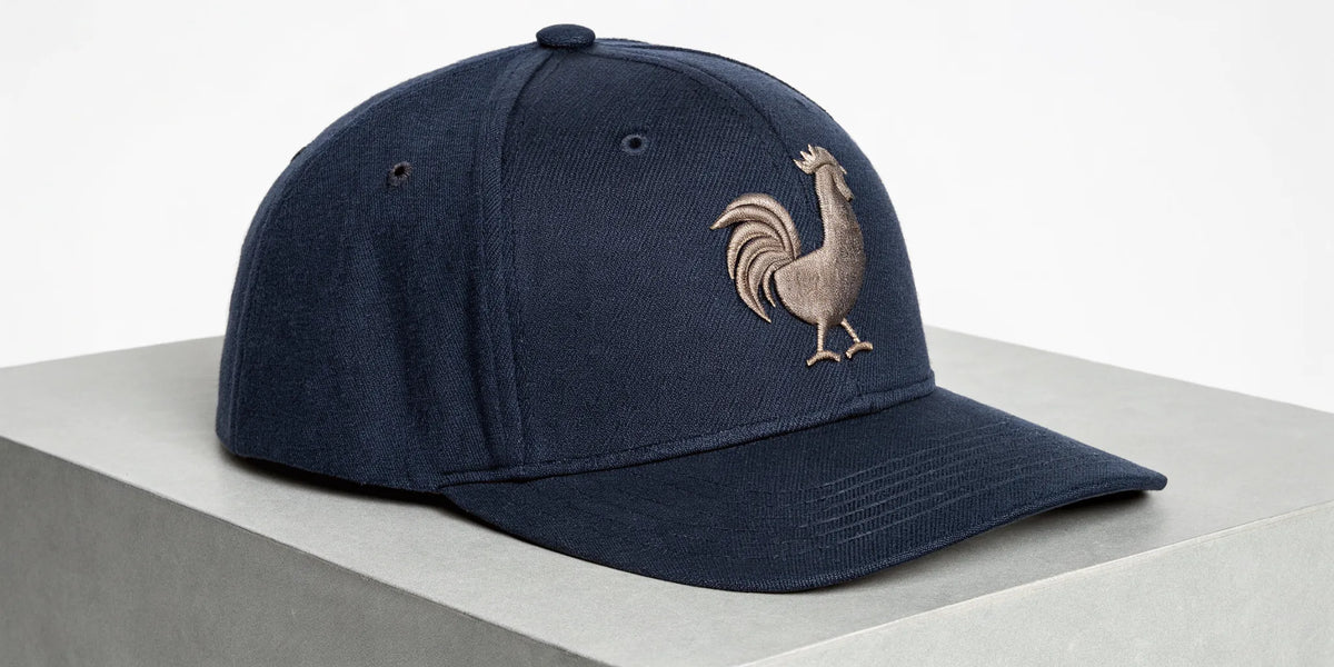 A premium navy blue Beisbol Gallo Fino hat with its signature embroidered rooster logo.