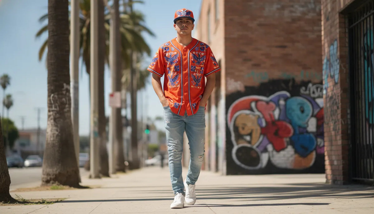 Mexican-American man in an embroidered Mexican state baseball jersey and beisbol cap walking a Los Angeles street, urban palm trees and street art in the background