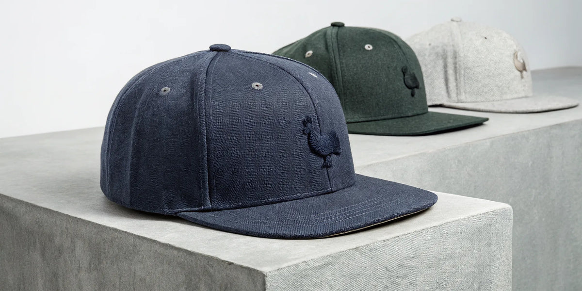 Beisbol Gallo Fino snapback hats in navy, green, and gray.