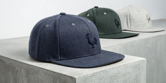 Beisbol Gallo Fino snapback hats in navy, green, and gray.