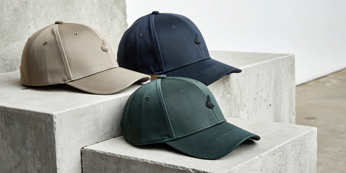 Beisbol Gallo Fino hats in tan, navy, and green with signature embroidery.